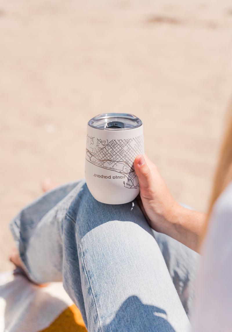 Person holding Santa Barbara Map Wine Tumbler Cup at a beach picnic